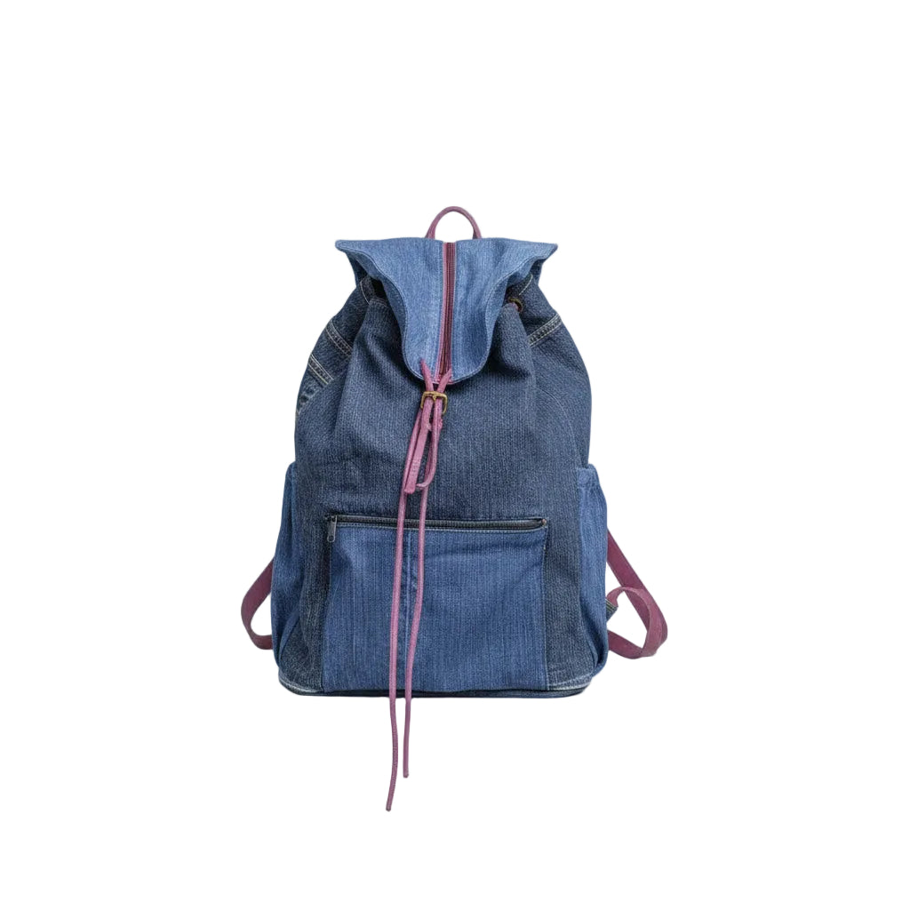 Person wearing a dark hoodie and ripped jeans, holding a blue denim jacket over their shoulder with a blurred outdoor background.